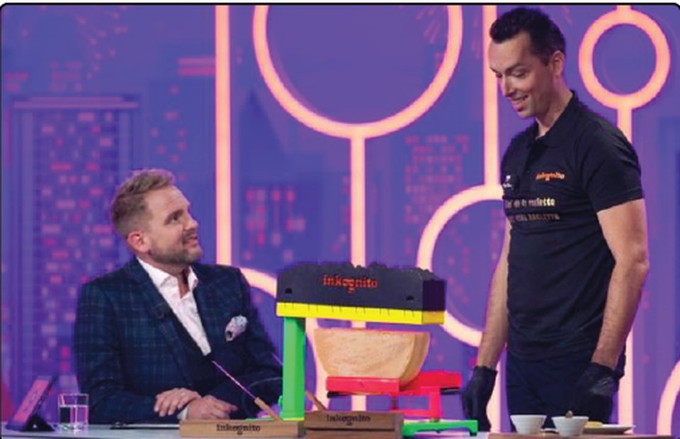 Milan Kolář with a TV host in a studio next to a raclette wheel on the Incognito show