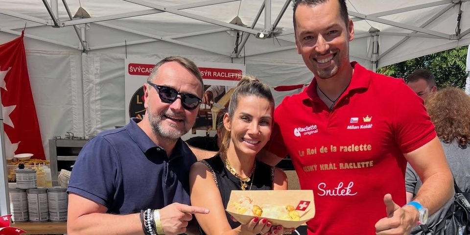 Guests with a plate of raclette at the Raclette Original stall, beside Milan Kolář